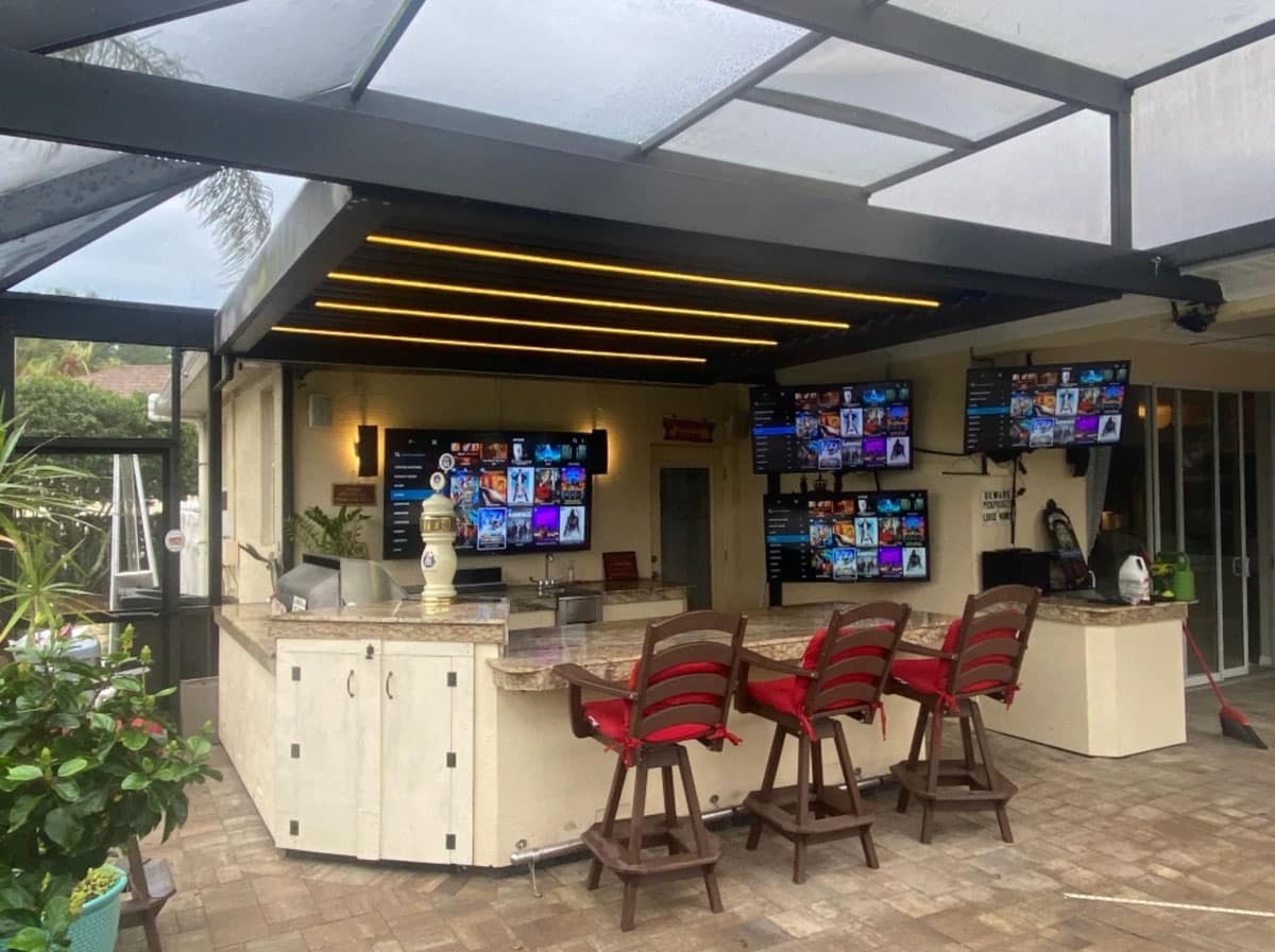 A screened in pergola with an outdoor kitchen
