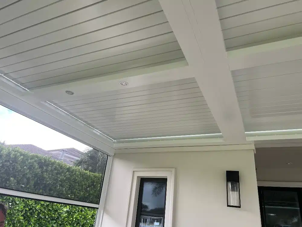 Motorized pergola ceiling with adjustable louvers and integrated lighting over covered patio