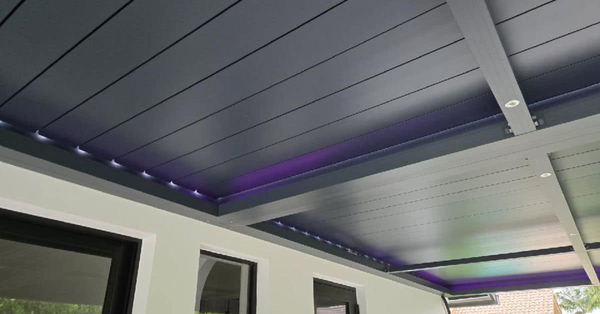 A close-up of a dark grey pergola ceiling featuring a combination of purple RGB perimeter lighting and white recessed lights in the support beams.